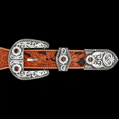 A custom western three piece belt buckle set featuring silver scrollwork and red zirconia stones